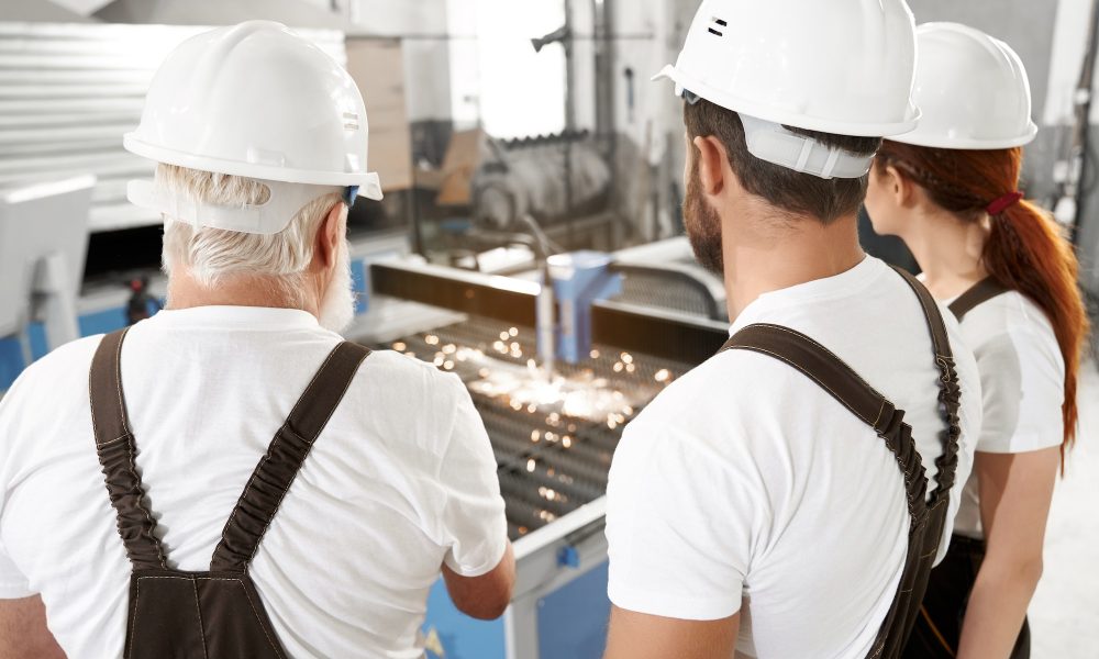 Engineers observing plasma laser cutting metal
