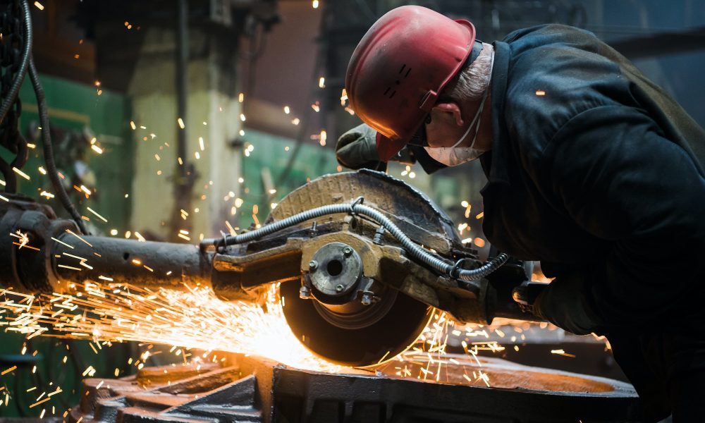 Worker grinding metal, metal grinding machine with sparks, metal sawing